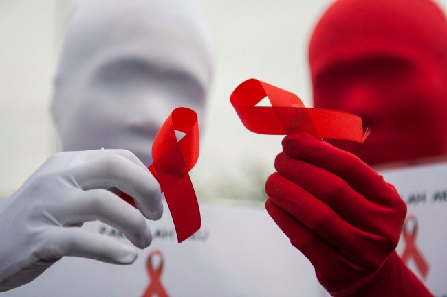 Egy indonéz aktivista az AIDS-ellenes kampányt jelképező piros szalagot mutatja az utcán az indonéziai Surabayában (Fotó: MTI/EPA/Fully Handoko)